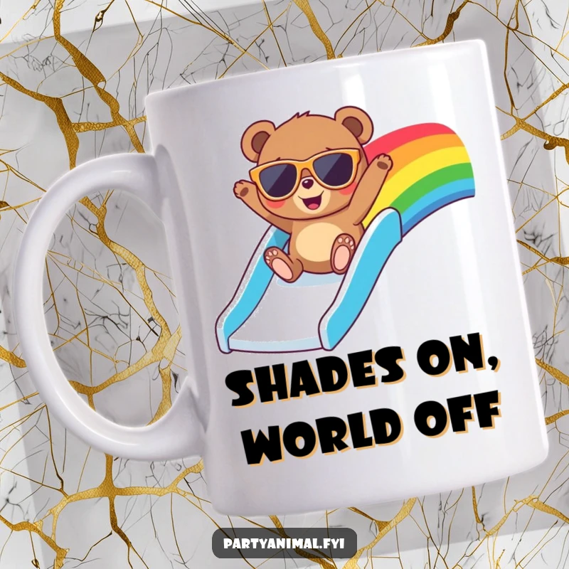 Funny mug featuring a bear in oversized sunglasses, joyfully sliding down a vibrant rainbow slide with a huge smile.