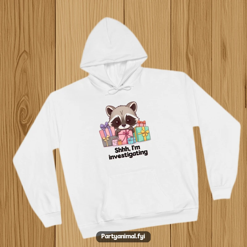 Funny hoodie featuring a curious raccoon character peeking out from behind wrapped gifts, perfect for those who love intrigue and humor.